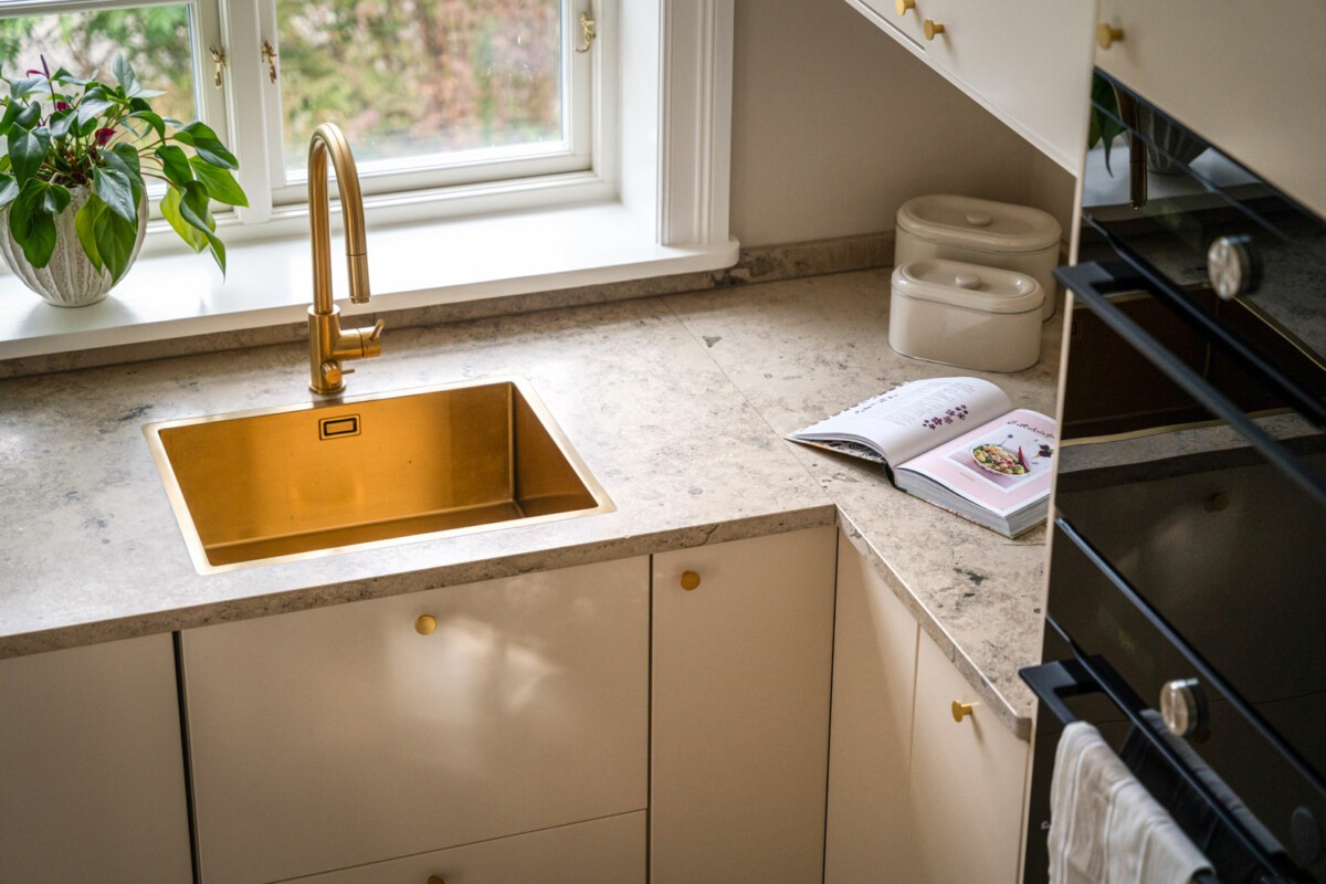 Grifo de cocina de color dorado con fregadero sobre una encimera de mármol  espacio de trabajo cómodo y hermoso diseño interior de cocina moderno