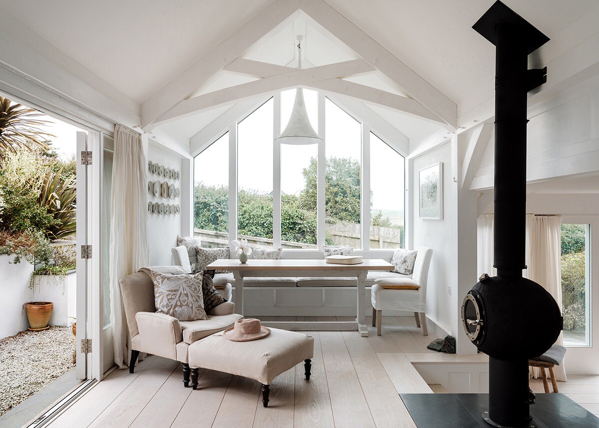 vigas en el techo blancas inspiración nórdica espacios multifuncionales diseño interior costero decoración estilo nórdico decoración con luz natural cornualles decoración costera casa rústica blanca casa inglesa casa en la costa atlántica arco gótico arco apuntado 
